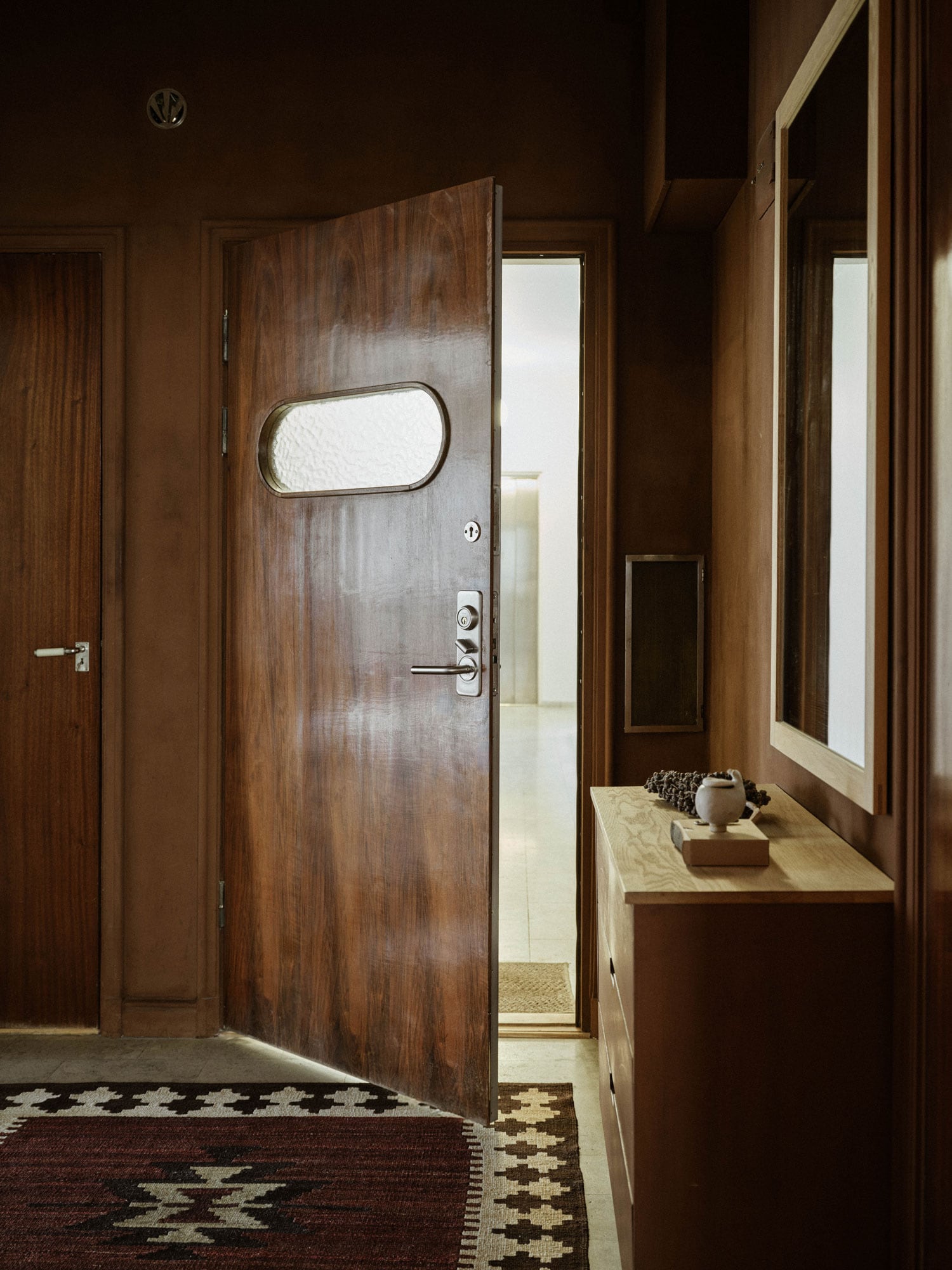 Gang med brune vegger og inngangsdøren på gløtt